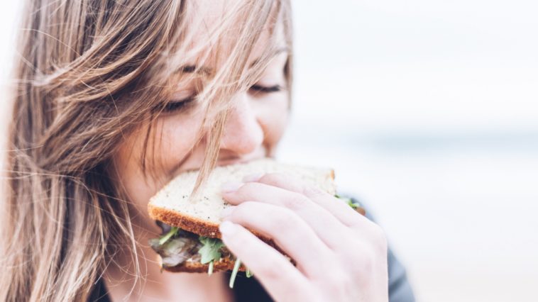 une femme mange un sandwich